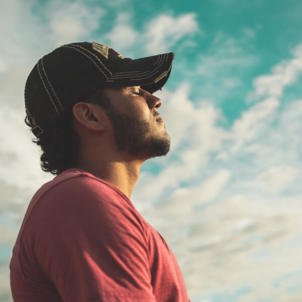 man meditating in front of cloudy sky