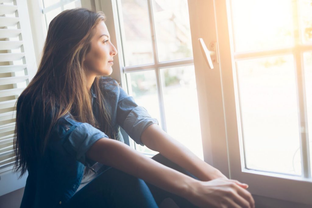 woman looking reflectively out of a window