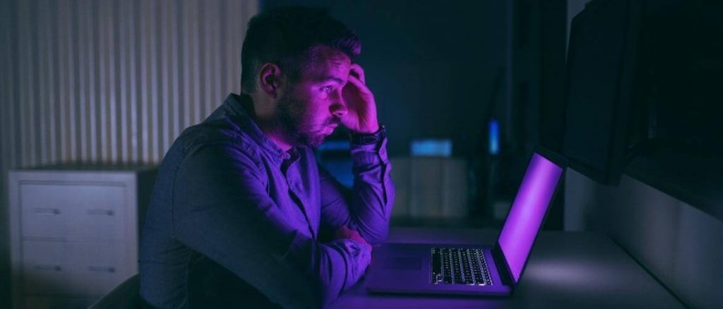 man looking at a purple computer screen