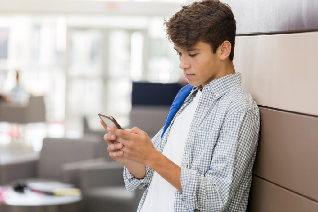 A teenage boy looking at his phone.