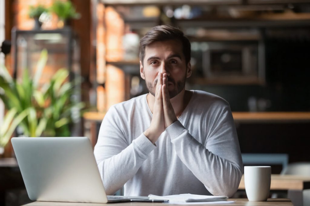 Man praying to God in front of his computer.