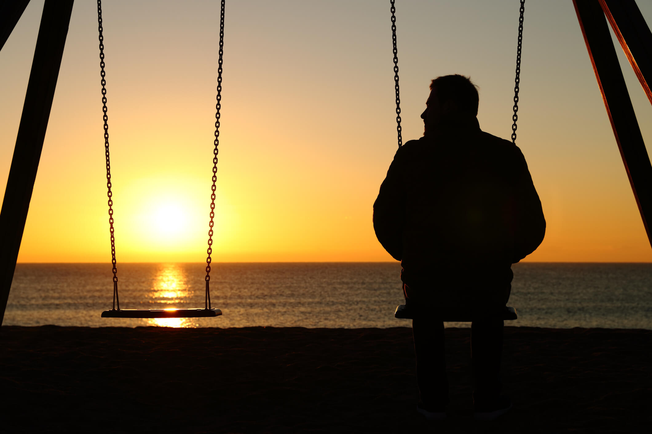 A man sitting alone on a swing.