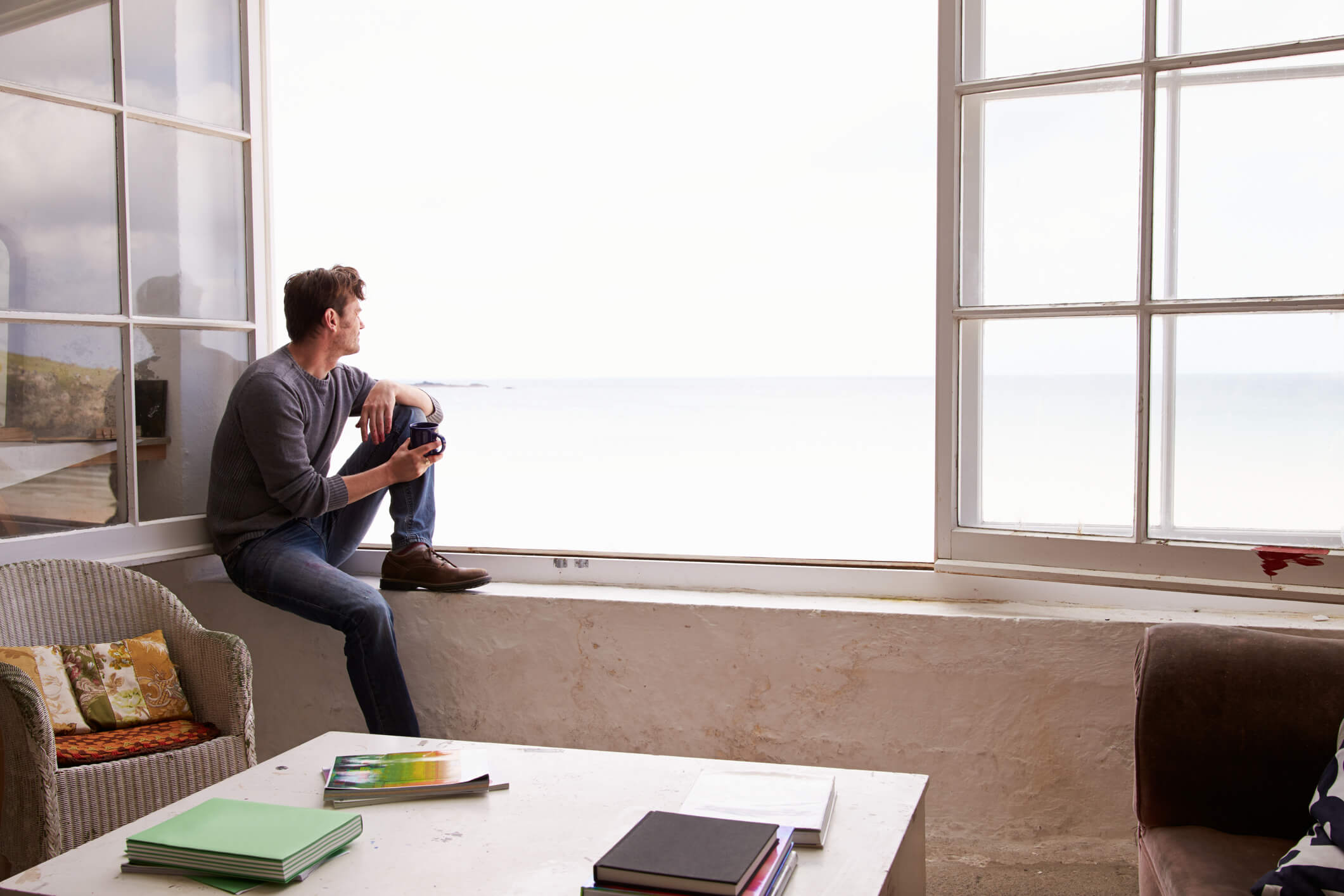 Man looking thoughtfully out of a large window.