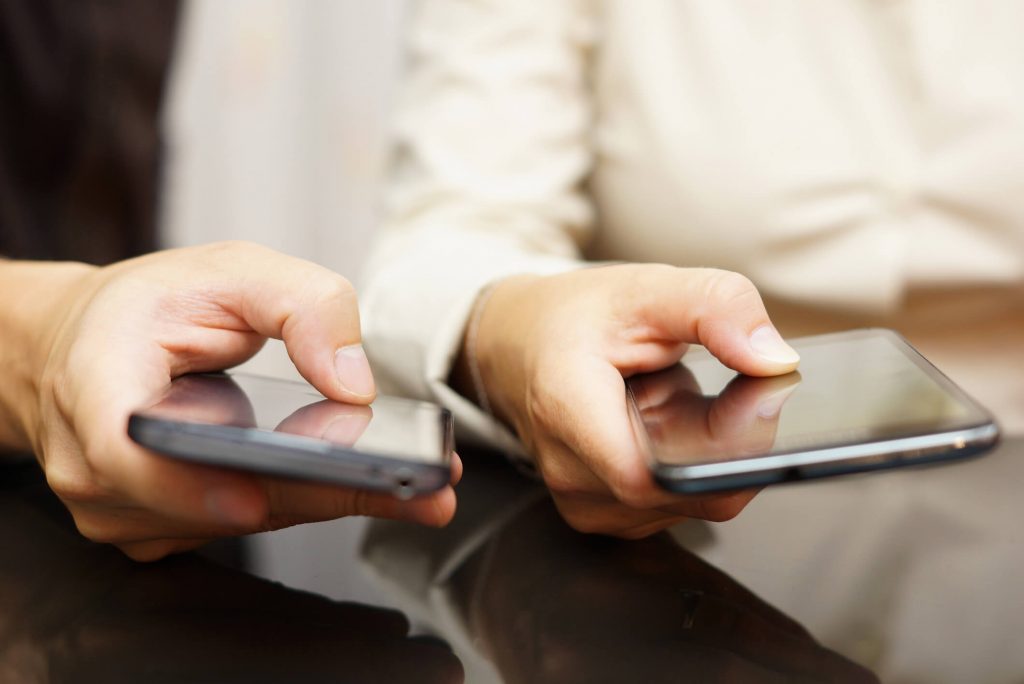 Close of up two people's hands as they download apps on their phones.