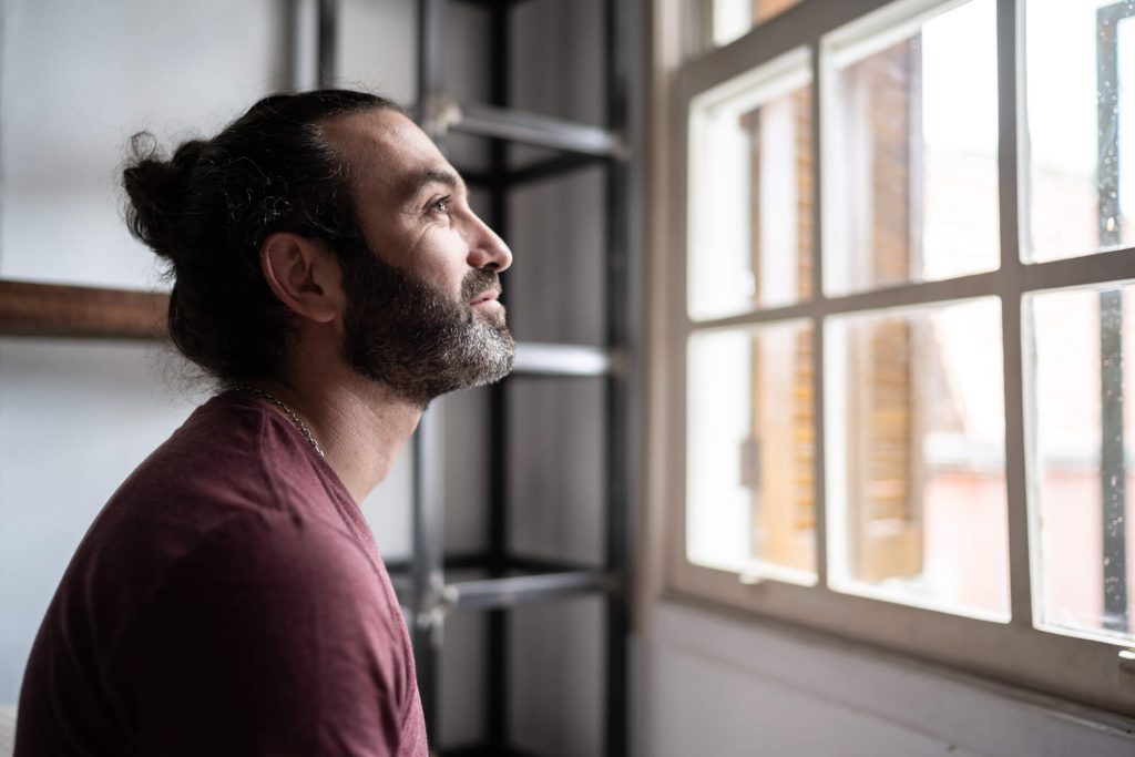 Man looking patiently out a window.