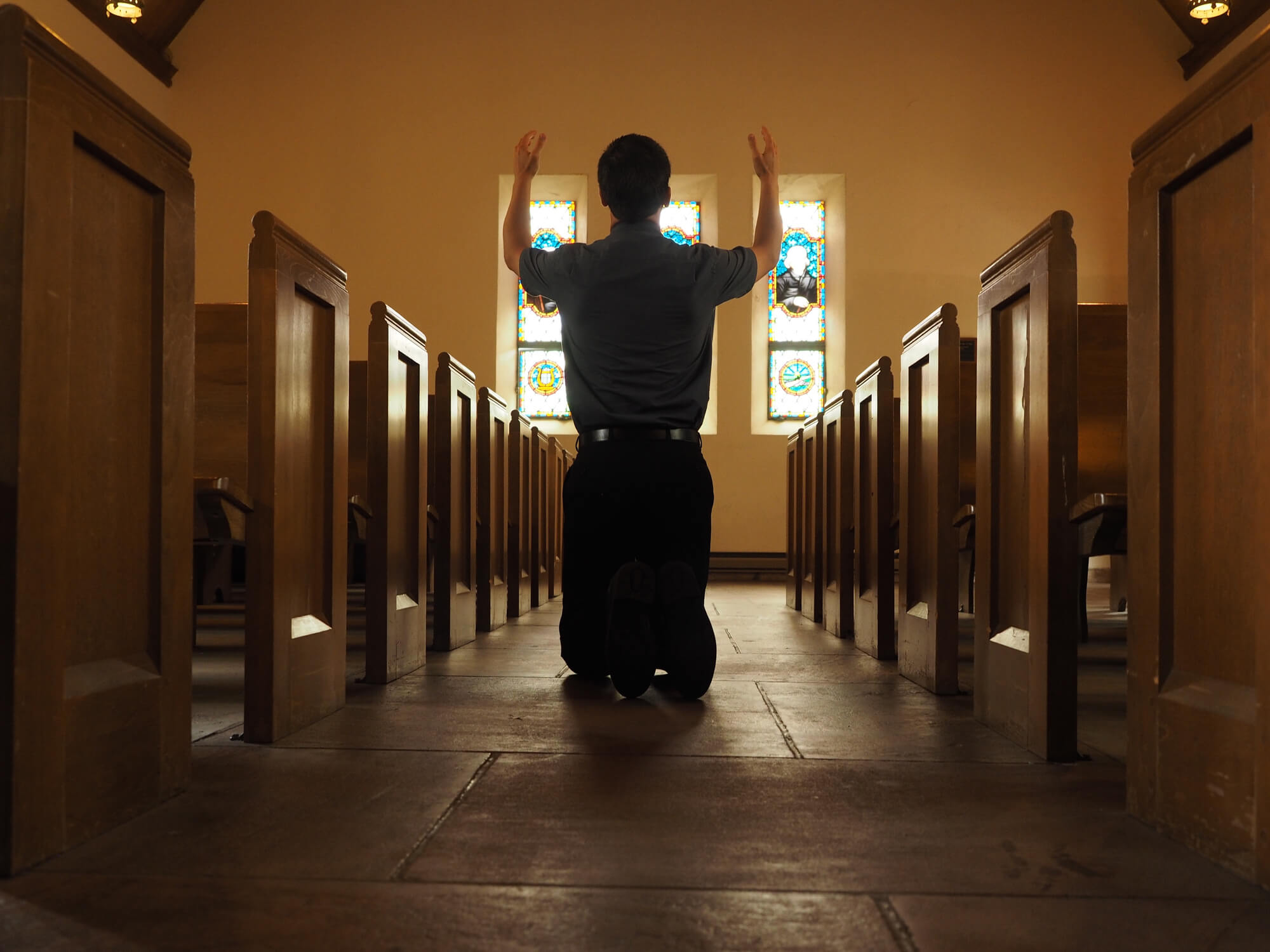 A man praying for his church in an empty sanctuary.