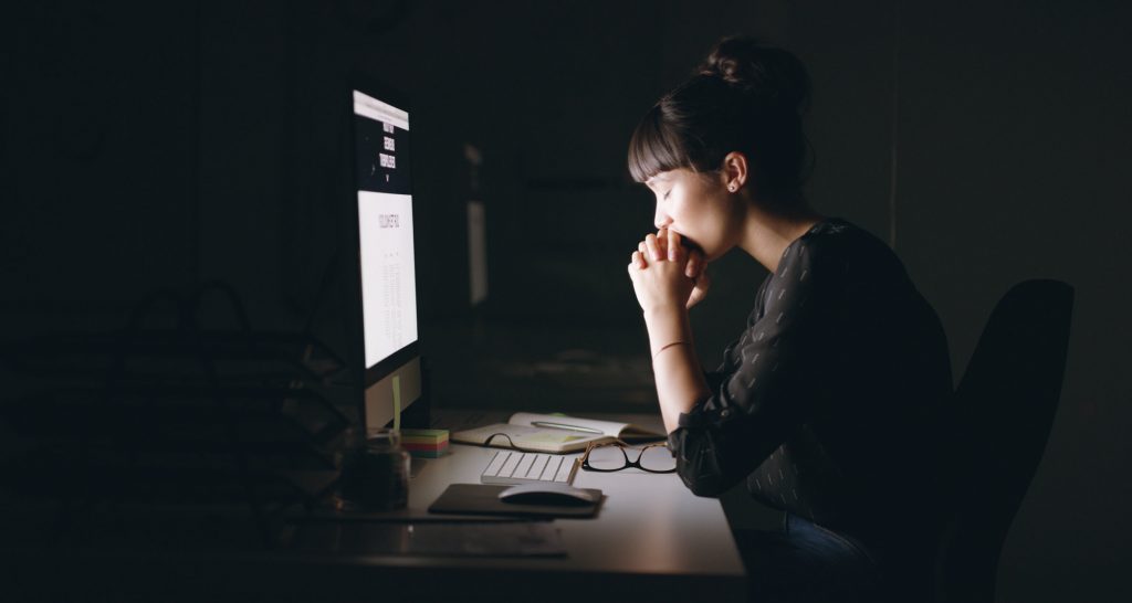 A young woman struggling with porn praying in front of her computer screen.