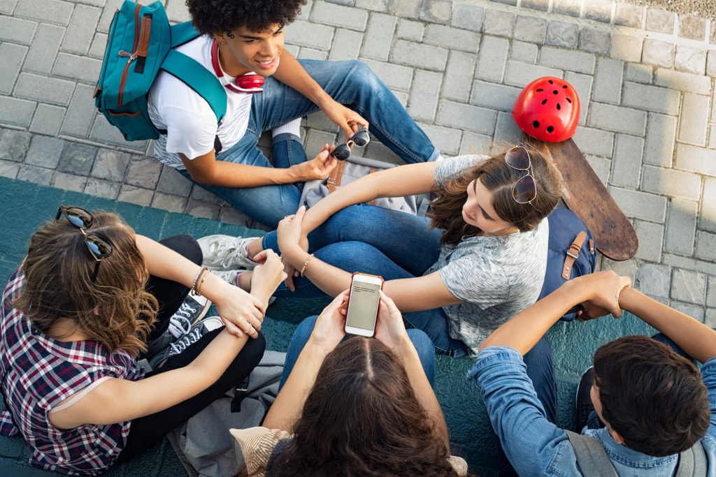 A group of teens sharing their smartphone screens.