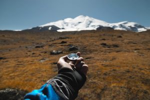 Hand holding a compass finding the path forward.