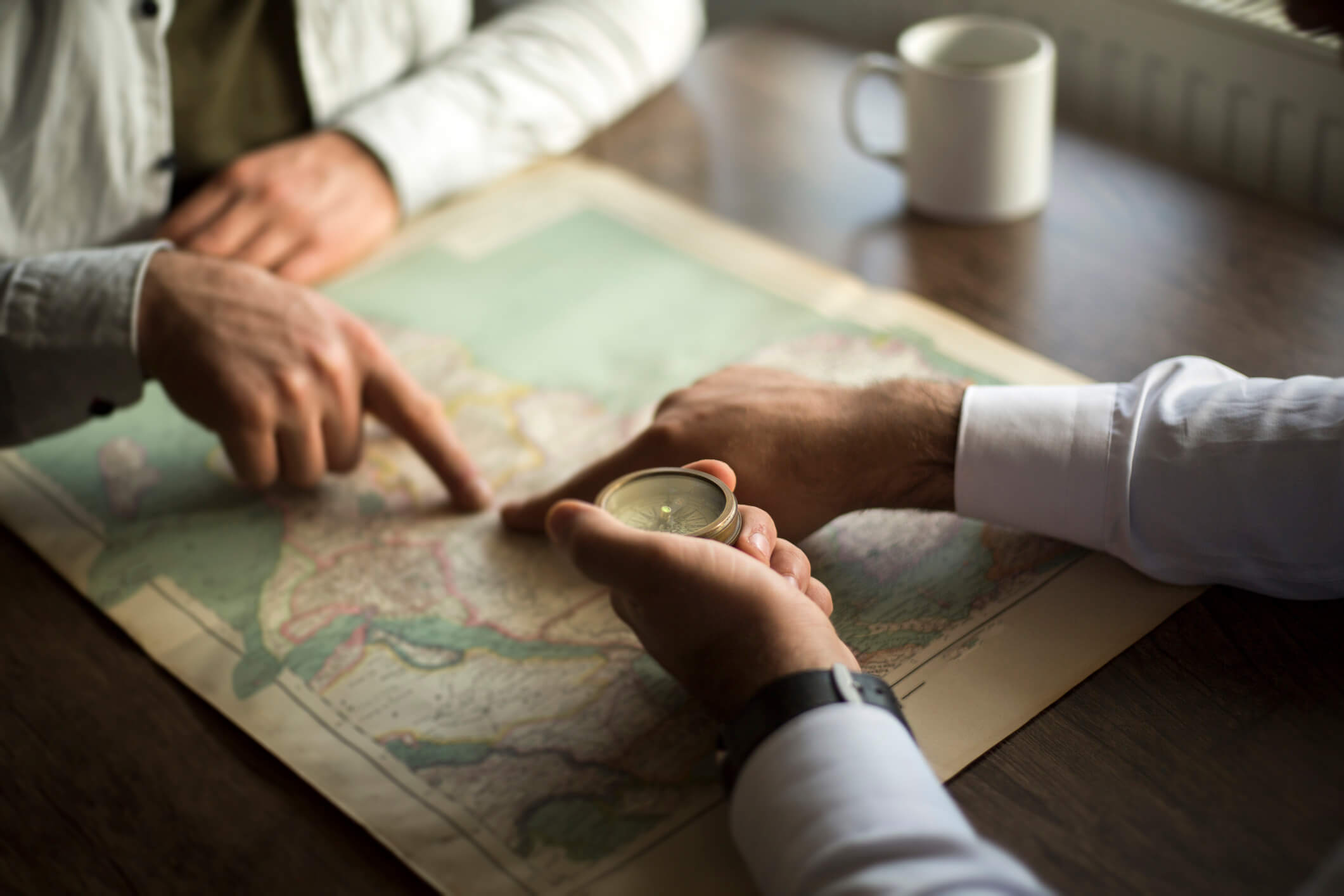 Two men are planning a journey with a map on a table.