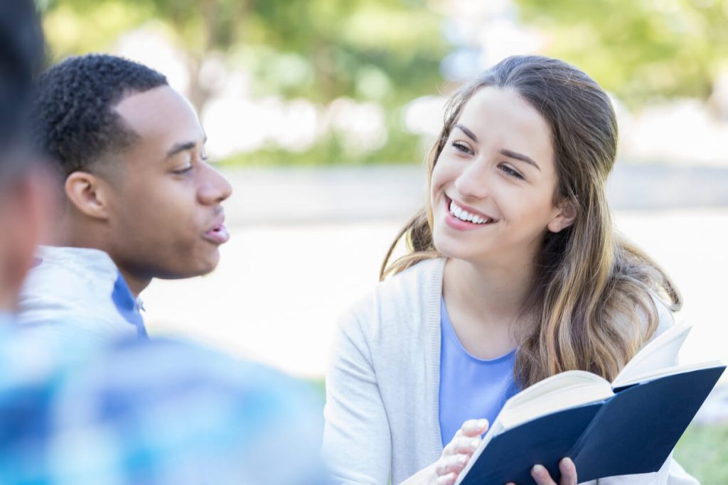 A young girl reading from the Bible with a young man.