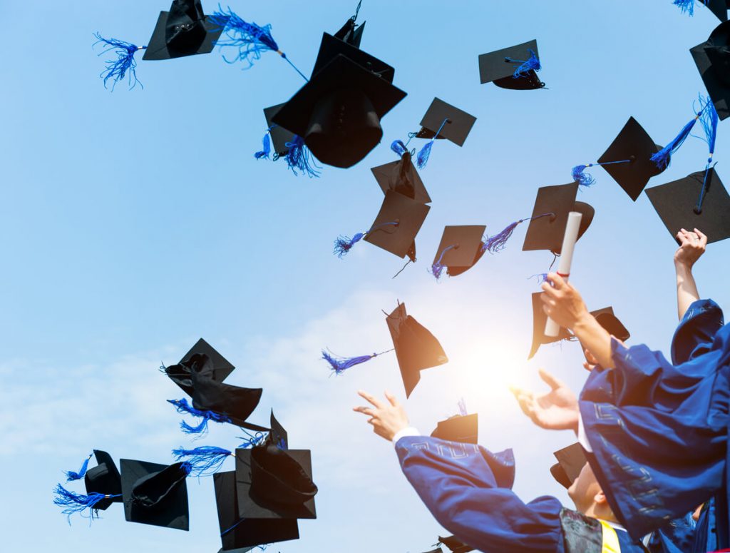 The hats of graduates against a blue sky, thrown in celebration.