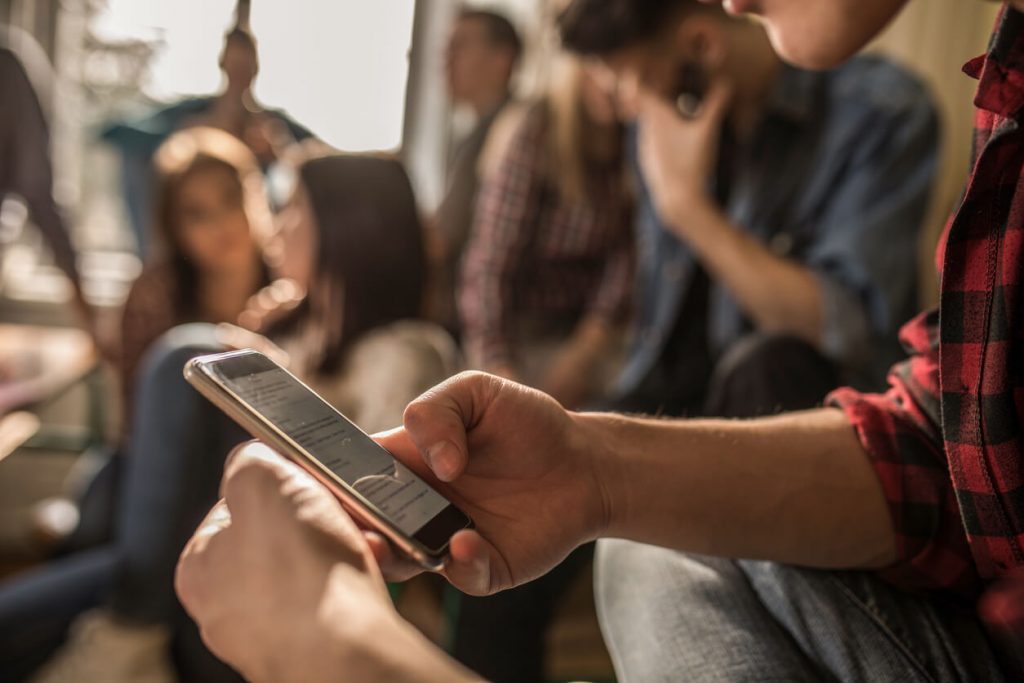 A high school student looking at his phone during class.