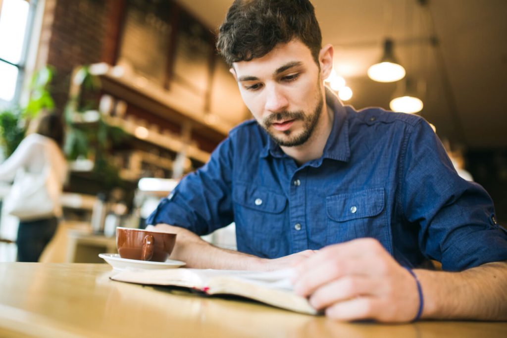 A young man his Bible in a coffee shop.