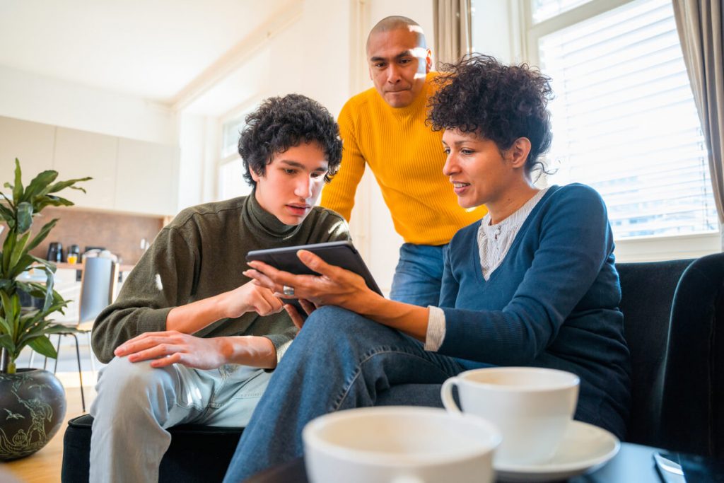 Parents with their teenage son looking at a tablet.