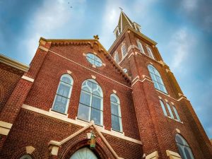 The front of a historic Catholic church against a blue sky.