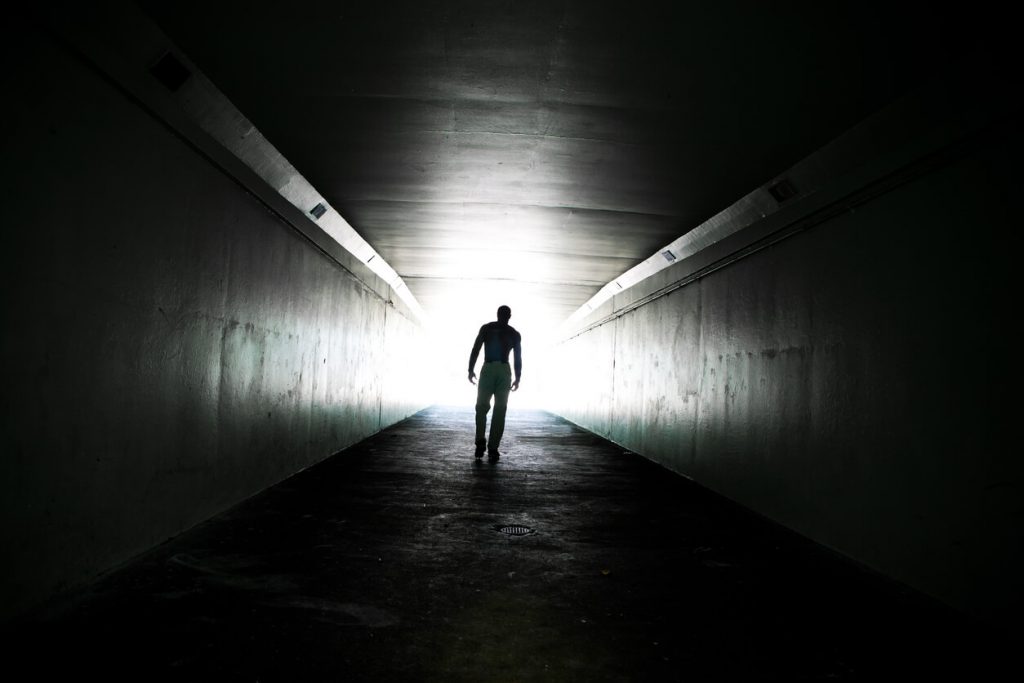 Silhouette of a man walking through a tunnel.