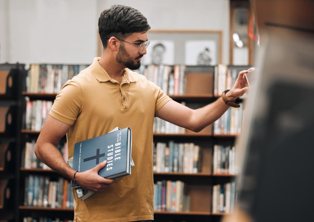 A young man studying lust in the Bible at the library.