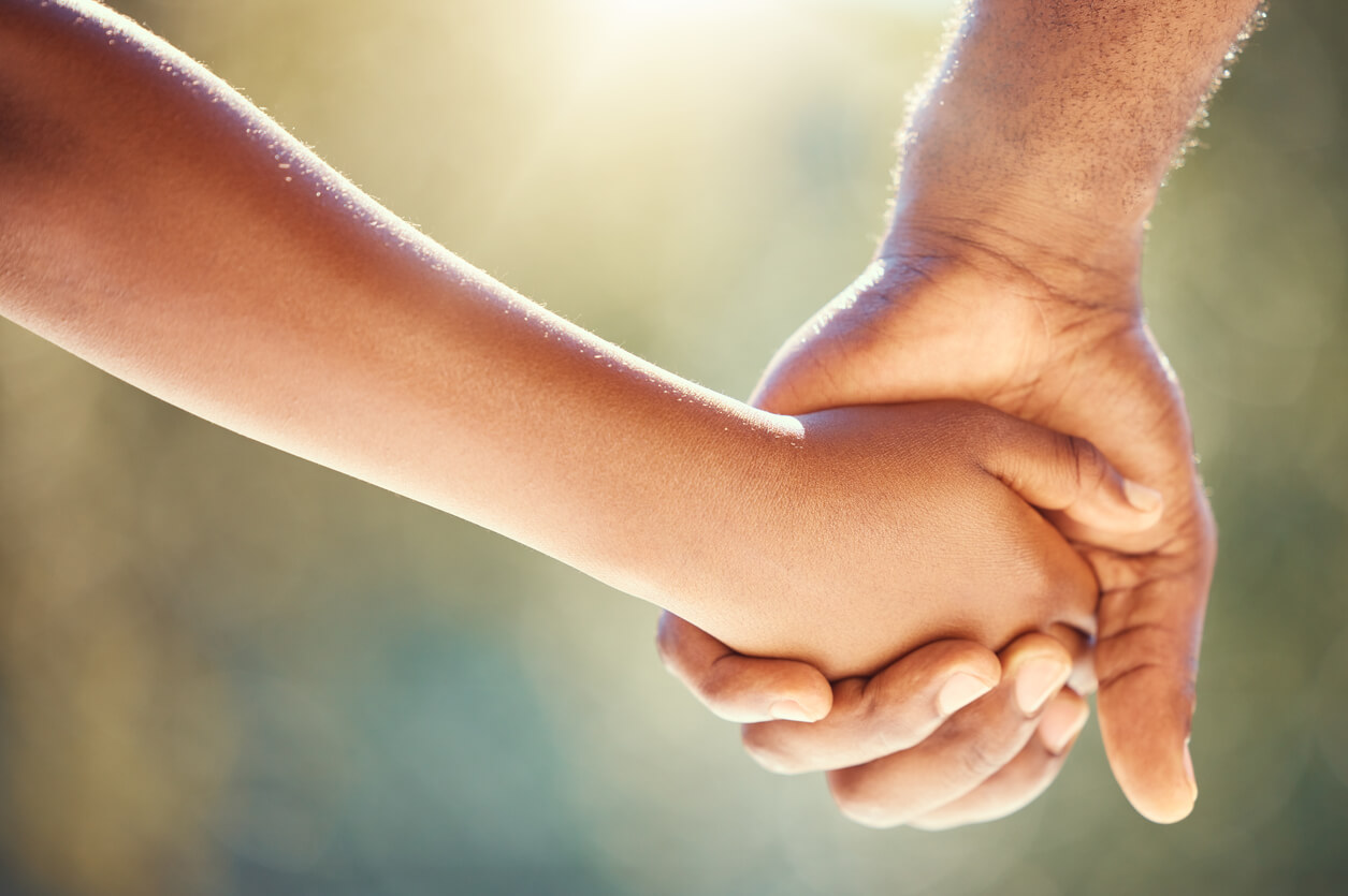 Close-up of parent holding a child's hand.