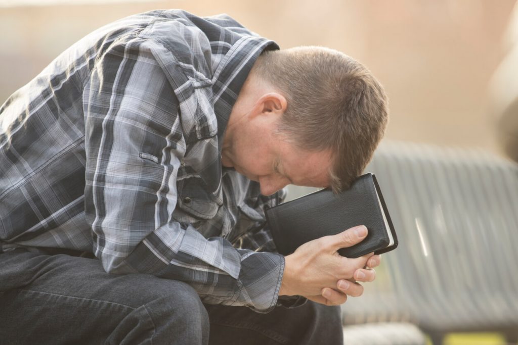 Man with a Bible praying.