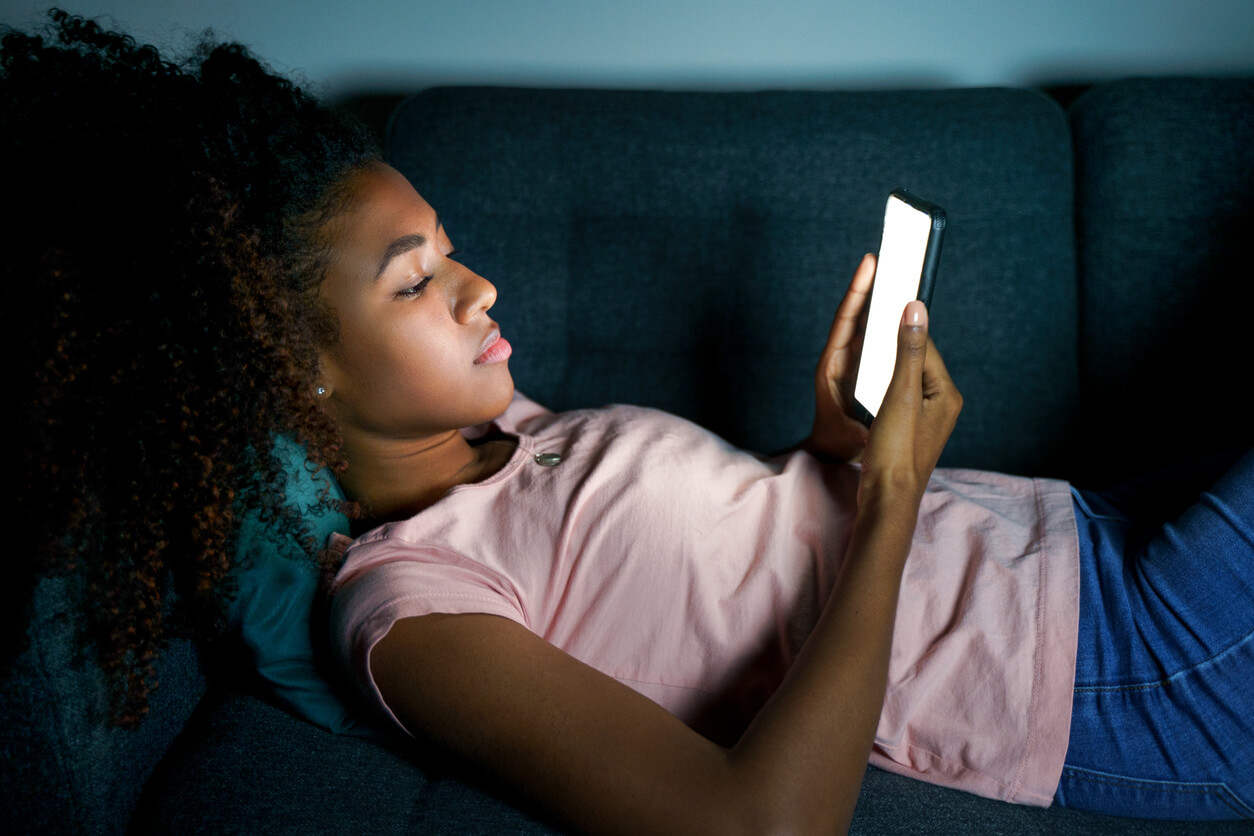 A teenage girl alone at night on her phone.