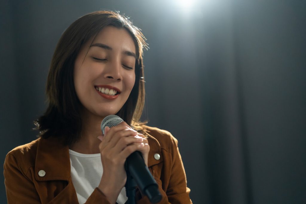 A young woman singing with a microphone in church.