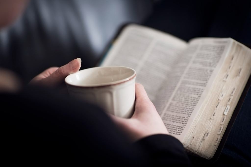 Woman reading the Bible with her cup of coffee.