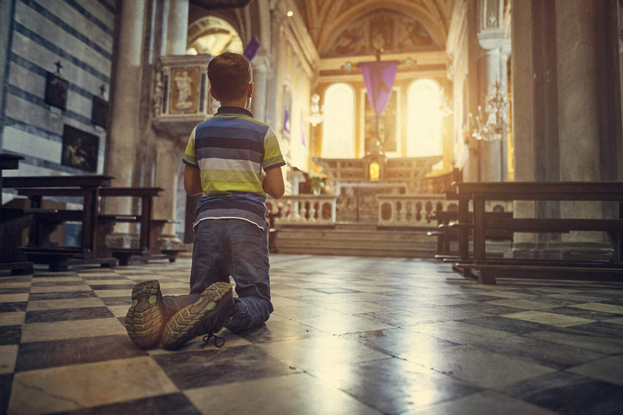 A young boy praying in a Catholic church.