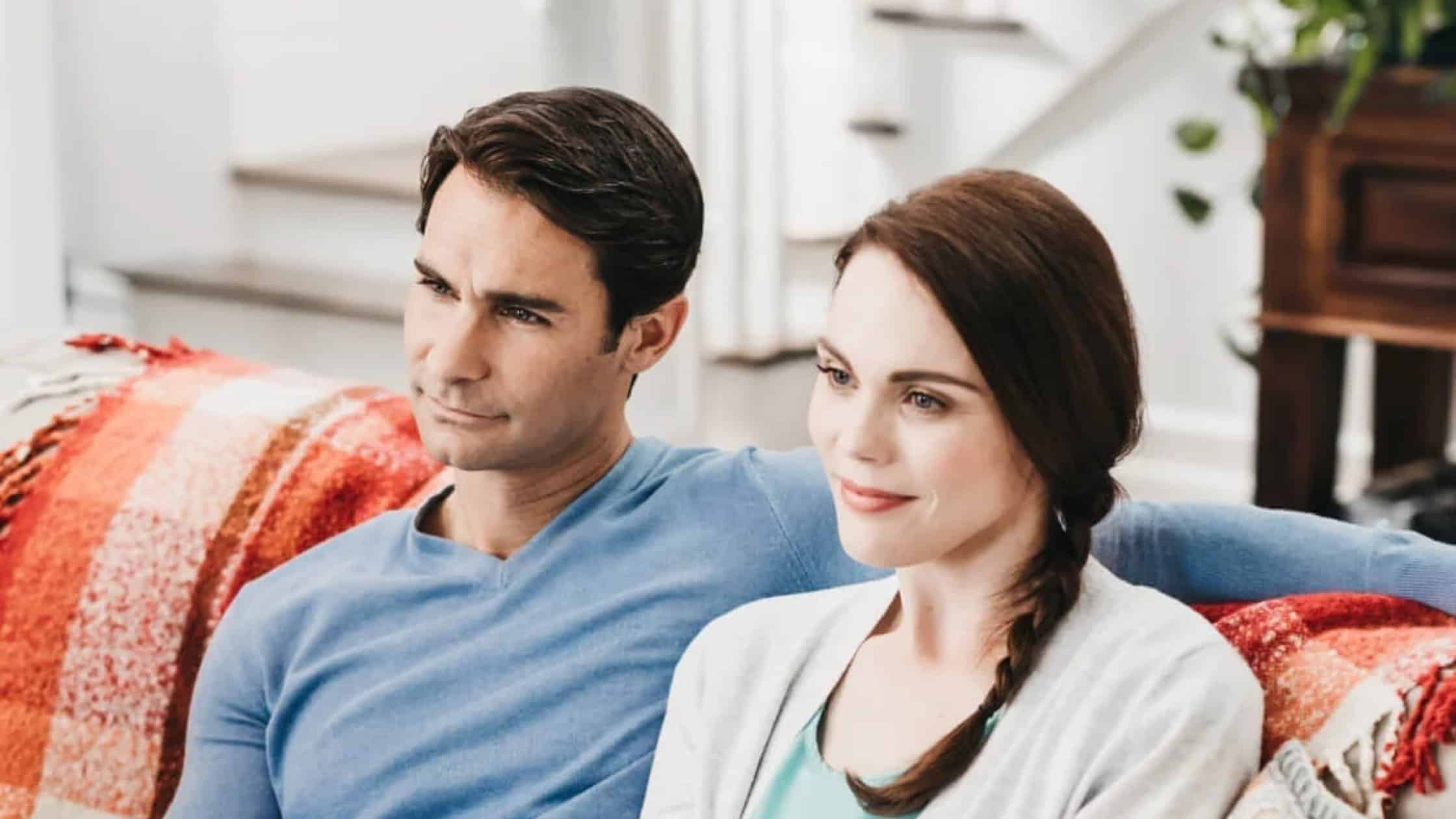 Husband and wife sitting next to each other on a couch.
