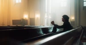 Young man kneeling in a church sanctuary.