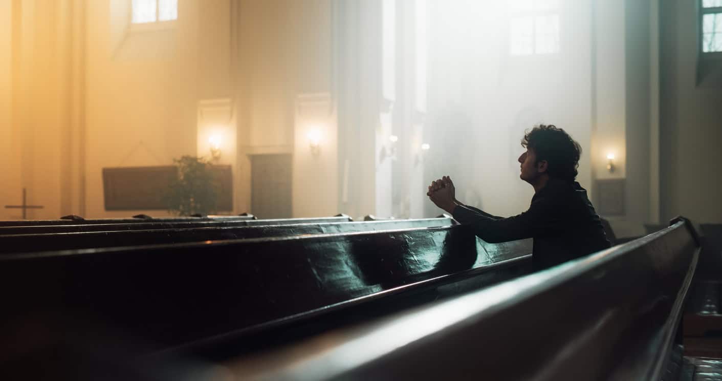 Young man kneeling in a church sanctuary.