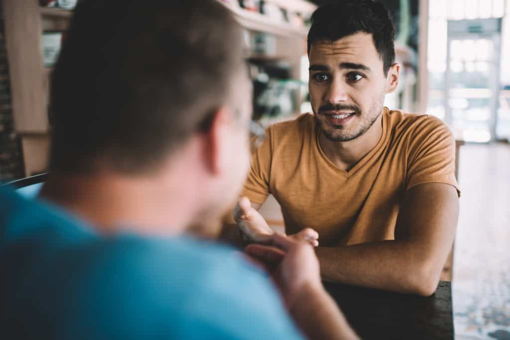 A concerned man talks to his friend.