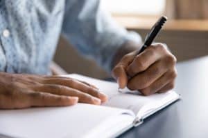 Close-up of a man writing in a notebook.