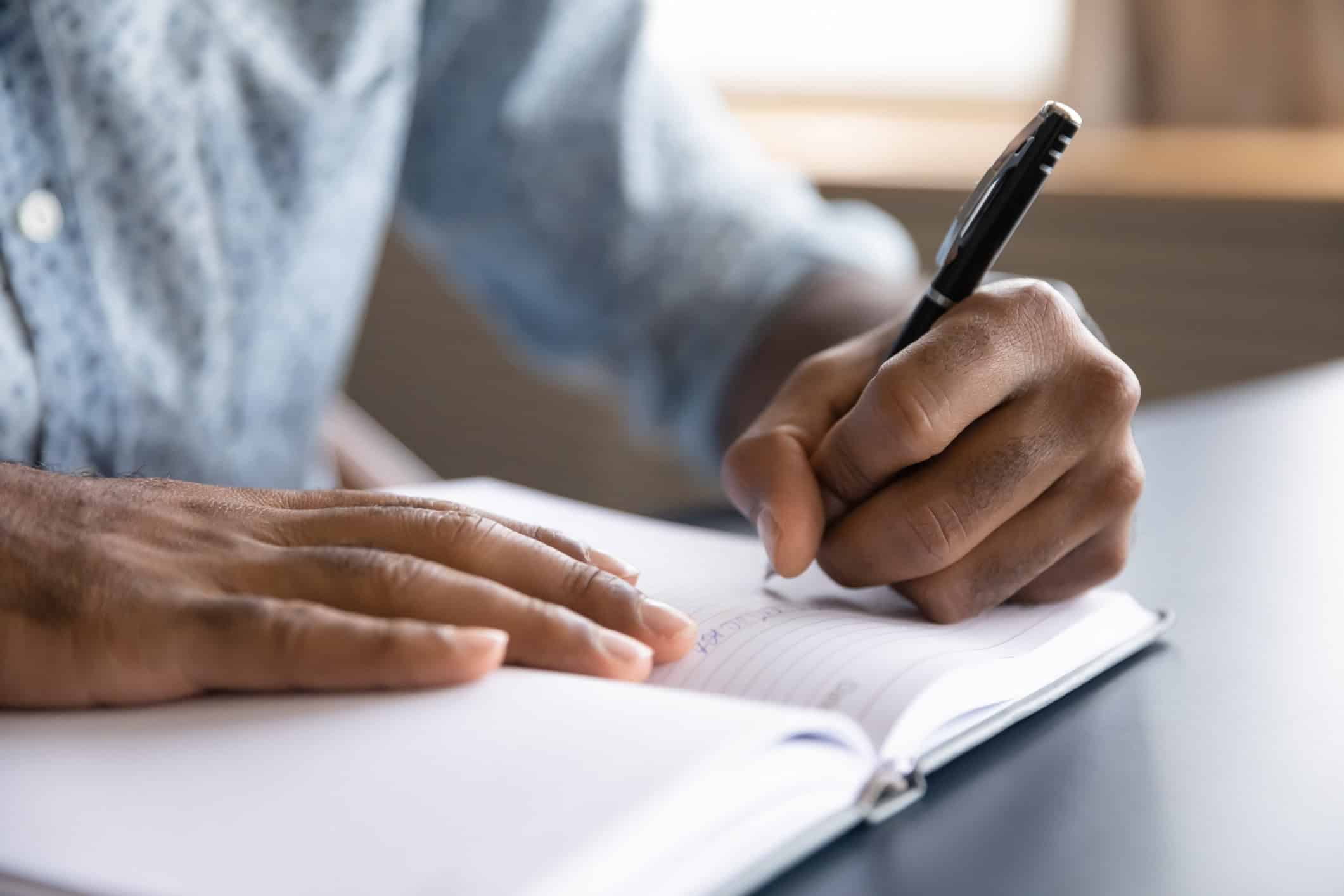 Close-up of a man writing in a notebook.