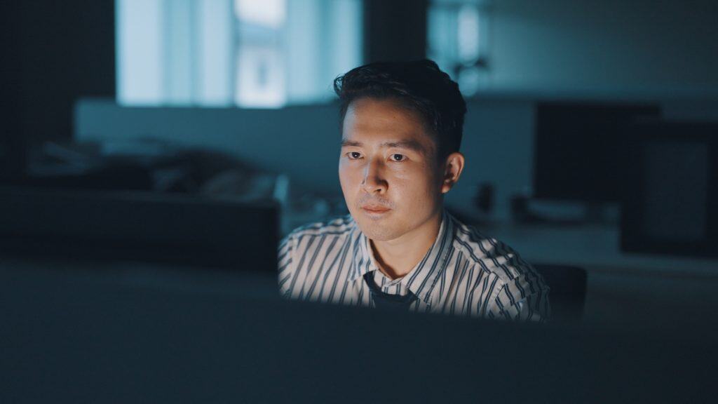 A man looking at his computer screen late at night.