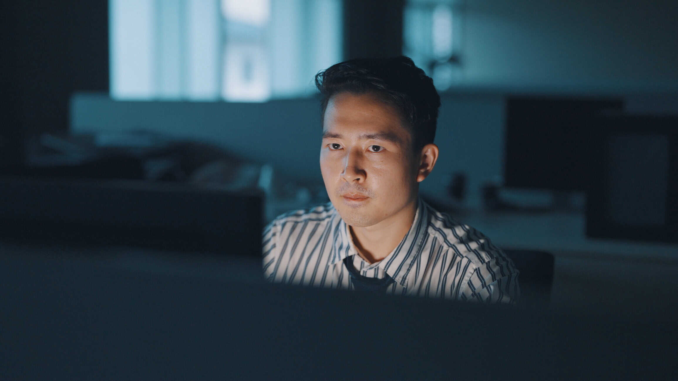 A man looking at his computer screen late at night.